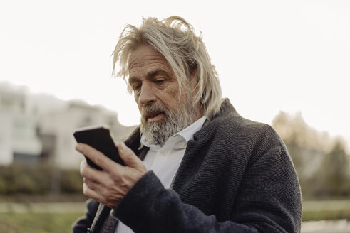 Ernster älterer Mann hält Handy im Freien - KNSF03374