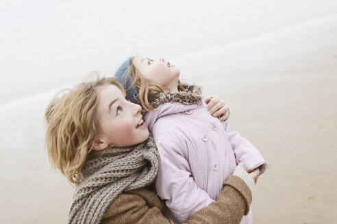 Brother nad his little sister on the beach in winter looking into the sky - KMKF00098