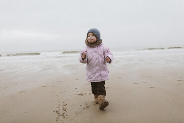 Deutschland, Nordseeküste, kleines Mädchen mit Lutscher beim Strandspaziergang im Winter - KMKF00099