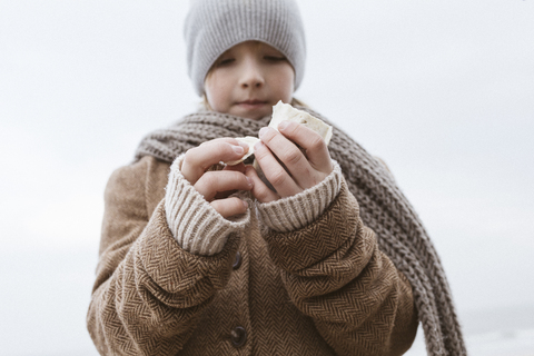 Boy's hands holding cuttlebone on the beach in winter stock photo