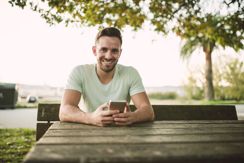 Porträt eines entspannten Mannes mit Mobiltelefon im Freien - RAEF01960