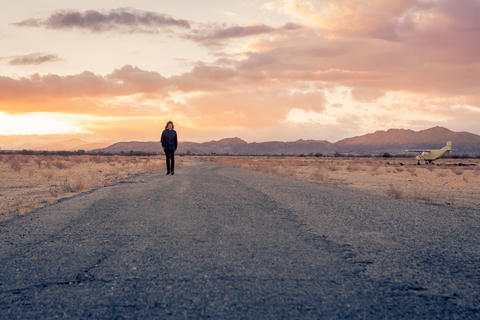USA, California, Joshua Tree, young guy walks along a road while sunset stock photo