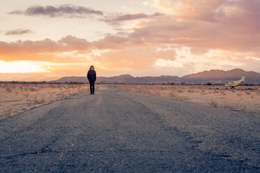 USA, Kalifornien, Joshua Tree, junger Mann geht bei Sonnenuntergang eine Straße entlang - WVF00856