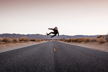 USA, California, Joshua Tree, young man jumping on a road - WVF00861