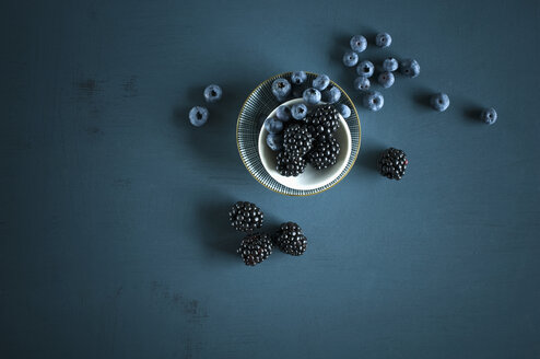 Blueberries and blackberries in bowls on blue ground - ASF06140