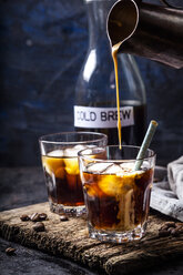 Pouring homemade vanilla flavoured coffee creamer into a glas with iced coffee - SBDF03425