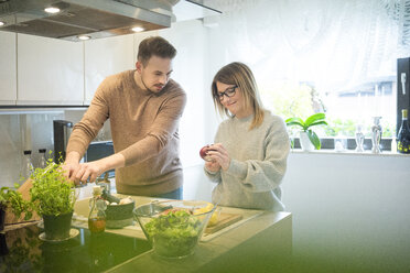 Couple preparing salad in kitchen together - MOEF00588