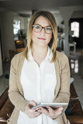 Portrait of smiling woman holding tablet at home - MOEF00592