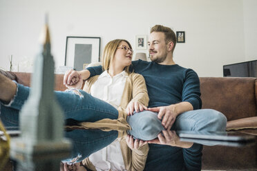 Couple sitting on couch at home with model of Empire State Building - MOEF00597