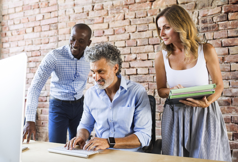 Smiling colleagues working together at desk in office stock photo