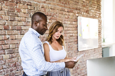 Two colleagues discussing paper in office - HAPF02611