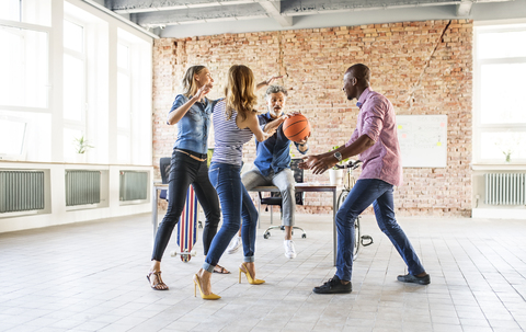Kollegen spielen Basketball im Büro, lizenzfreies Stockfoto