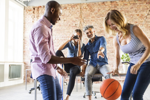 Frau macht Foto von Kollegen, die im Büro Basketball spielen - HAPF02627