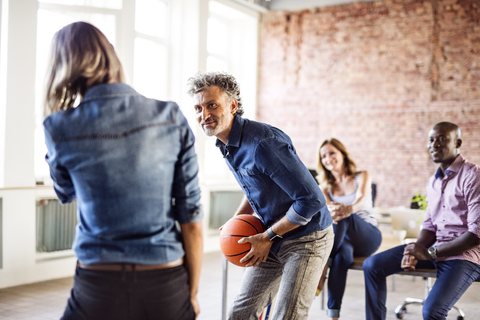 Kollegen spielen Basketball im Büro, lizenzfreies Stockfoto