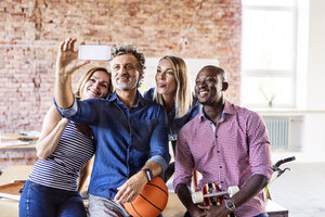Glückliche Kollegen mit Basketball im Büro machen ein Selfie - HAPF02631