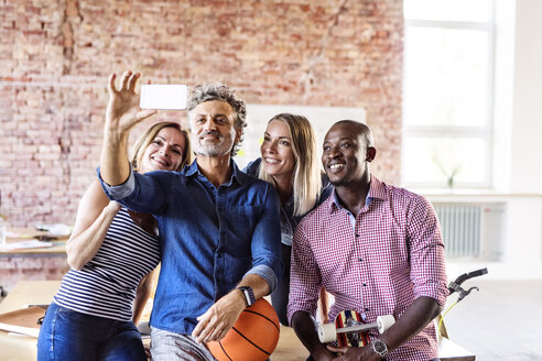 Glückliche Kollegen mit Basketball im Büro machen ein Selfie - HAPF02632