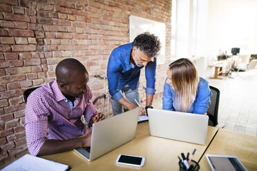 Geschäftsleute mit Laptops bei der Arbeit am Schreibtisch im Büro - HAPF02644