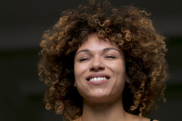 Porträt einer glücklichen Frau mit geschlossenen Augen vor einem schwarzen Hintergrund - HHLMF00013