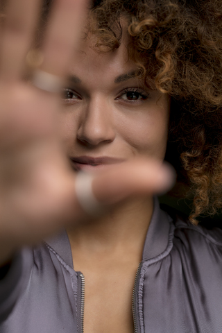 Porträt einer lächelnden jungen Frau, die ihre Hand hebt, lizenzfreies Stockfoto