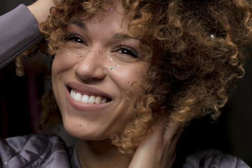 Porträt einer glücklichen Frau mit Konfetti im Gesicht - HHLMF00027