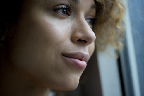 Portrait of smiling woman looking out of window - HHLMF00056