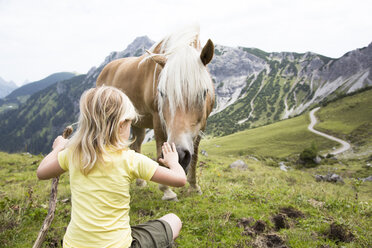 Österreich, Südtirol, junges Mädchen mit Pferd auf Wiese - FKF02866