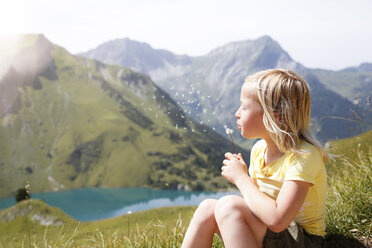 Austria, South Tyrol, young blond girl blowing blowball - FKF02870