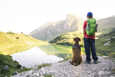 Austria, South Tyrol, young boy standing next to his dog - FKF02881