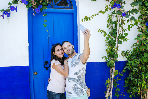 Marokko, Tanger, Paar macht Selfie mit Smartphone vor blauer Tür, lizenzfreies Stockfoto