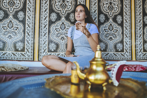 Marokko, Porträt einer Frau mit Henna-Tätowierung auf der Hand, die ein Glas Tee trinkt, lizenzfreies Stockfoto