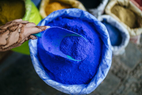 Marokko, Chefchaouen, mit Henna-Tätowierung bemalte Frauenhand, die eine Kelle mit blauen Pigmenten hält - KIJF01808