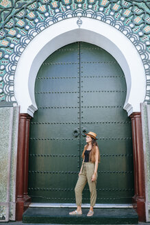 Marokko, Chefchaouen, Frau vor grünem Portal stehend - KIJF01813