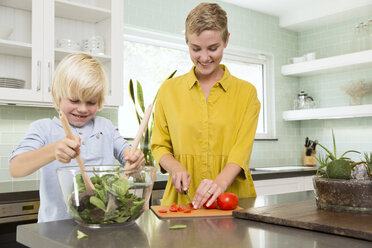 Smiling mother and son preparing salad in kitchen together - MFRF01070