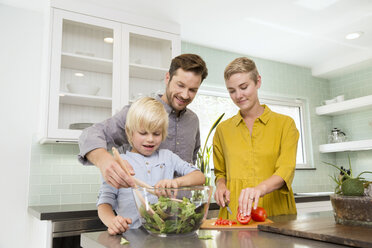 Smiling family preparing salad in kitchen together - MFRF01071