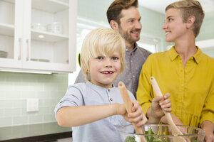 Lächelnde Familie bei der gemeinsamen Zubereitung von Salat in der Küche - MFRF01072