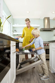 Junge hilft Mutter beim Ausräumen der Spülmaschine in der Küche - MFRF01081