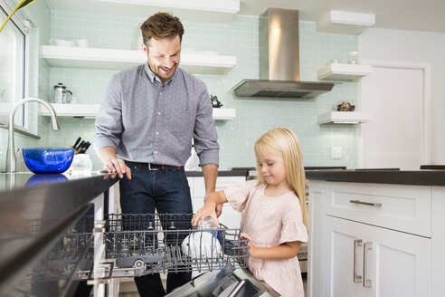 Mädchen hilft Vater beim Ausräumen der Spülmaschine in der Küche - MFRF01083