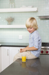 Boy in kitchen with glass of orange juice - MFRF01087