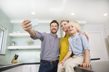 Father taking selfie with his family in kitchen - MFRF01095