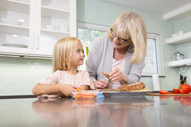 Großmutter und Enkelin bereiten in der Küche gemeinsam eine Lunchbox vor - MFRF01100
