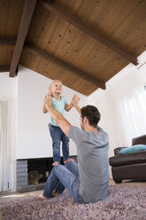 Vater spielt mit Tochter auf Teppich im Wohnzimmer zu Hause - MFRF01115