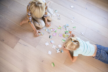 Bruder und Schwester liegen zu Hause auf dem Boden und spielen ein Puzzle - MFRF01120