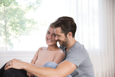 Smiling couple relaxing at home in front of window - MFRF01123