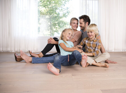 Entspannte Familie, die zu Hause auf dem Boden sitzt - MFRF01126