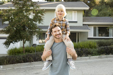 Portrait of boy on father's shoulders in front of their home - MFRF01129
