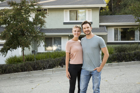 Portrait of smiling couple in front of their home - MFRF01131