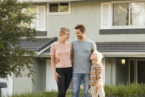 Lächelnde Eltern mit Junge vor ihrem Haus stehend, lizenzfreies Stockfoto