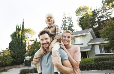 Portrait of smiling parents with son in front of their home - MFRF01136