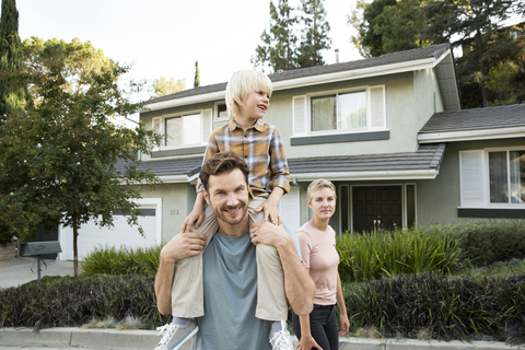 Portrait of smiling parents with son in front of their home stock photo
