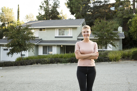 Porträt einer lächelnden Frau vor ihrem Haus, lizenzfreies Stockfoto